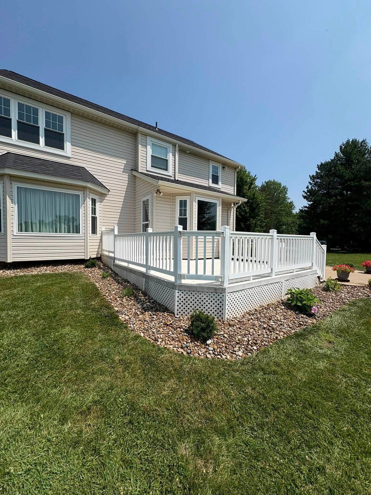Corner mulch bed and new shrubs beside a white deck