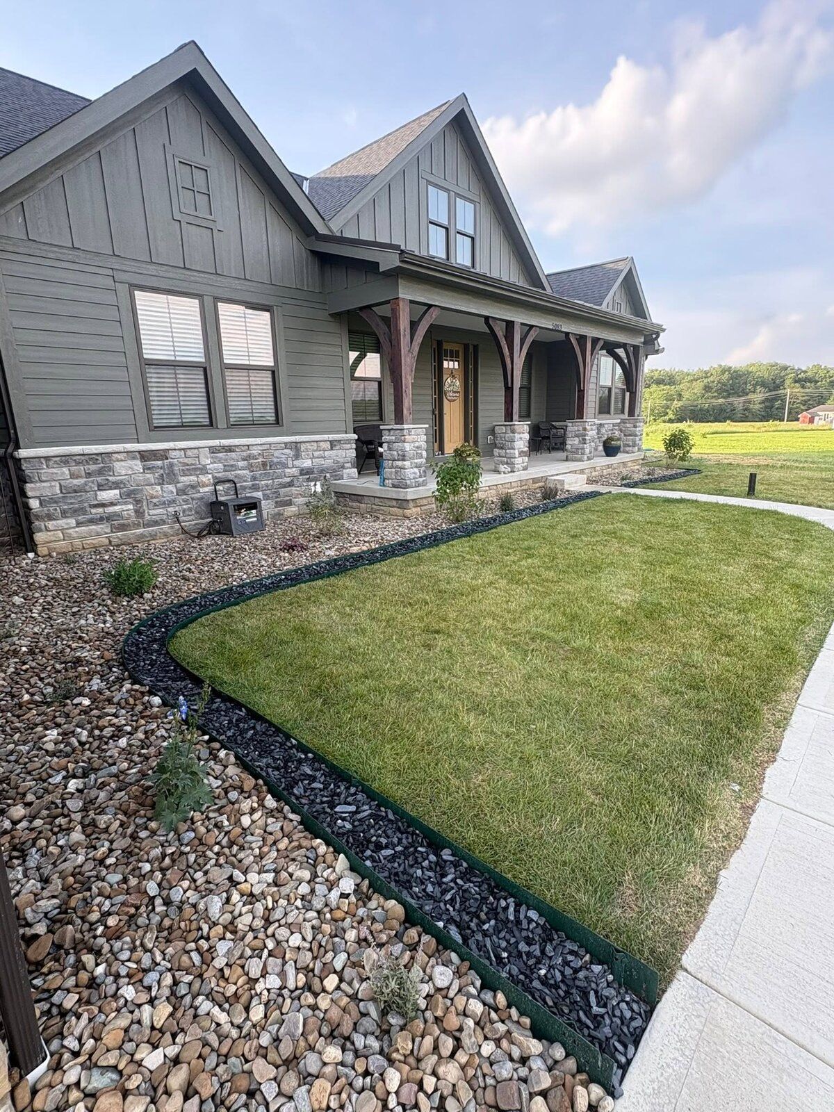 Mulch bed with crisp black edging and river rock at a craftsman home