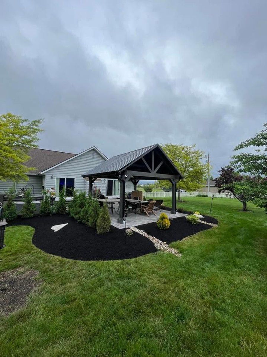 Pavilion and paver patio framed by fresh curved mulch beds